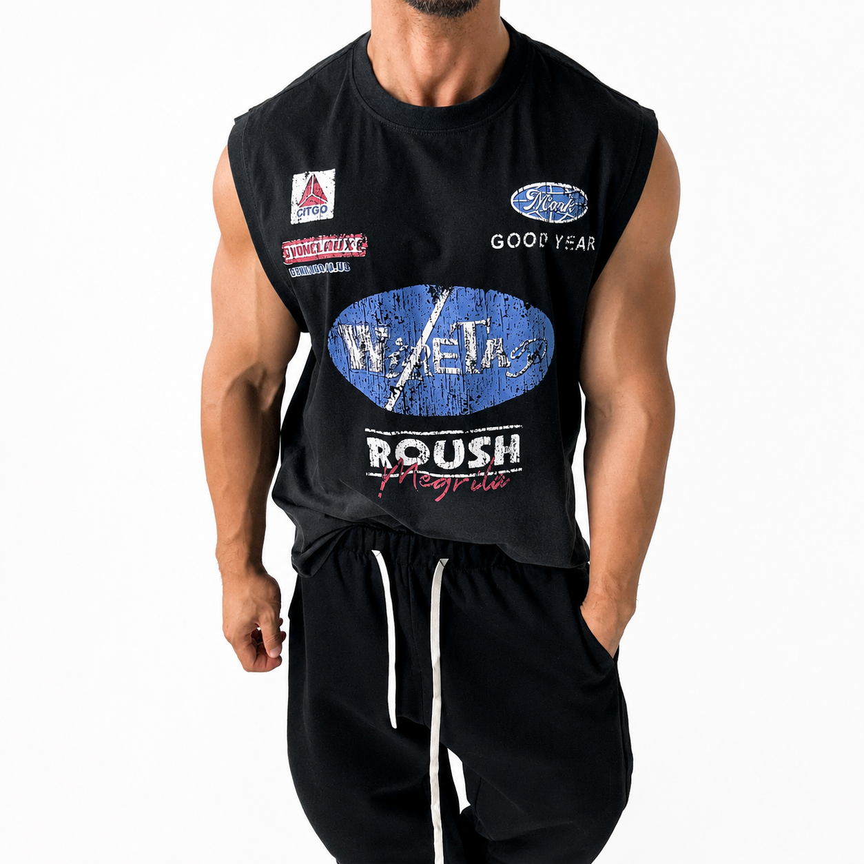 Men's black sleeveless graphic tank top worn with black casual pants.